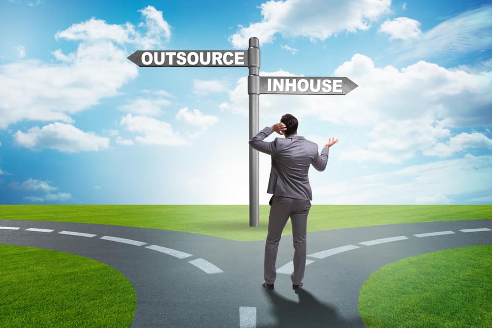 Businessman,At,Crossroads,Deciding,Between,Outsourcing,And,Inhou